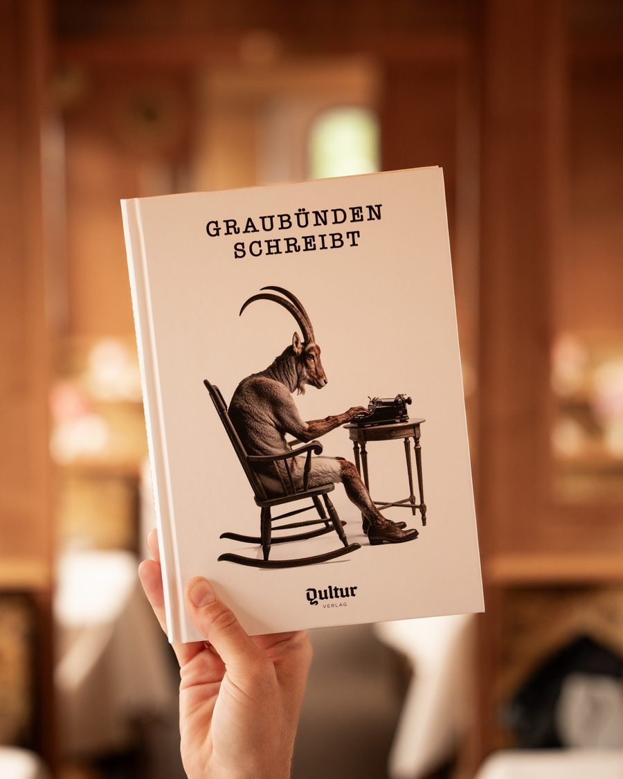 Eine Hand hält das Buch «Graubünden schreibt» hoch, dahinter unscharf der holzgetäfelte Speisewagen mit gedeckten Tischen