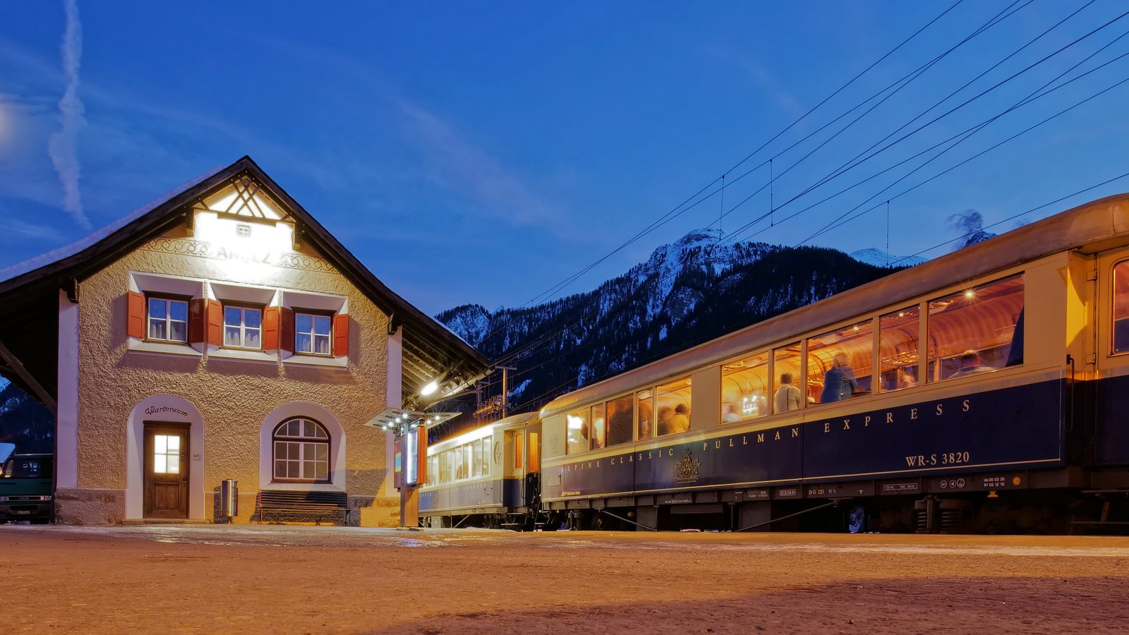 Der Zug am verschneiten Bahnhof zur blauen Stunde