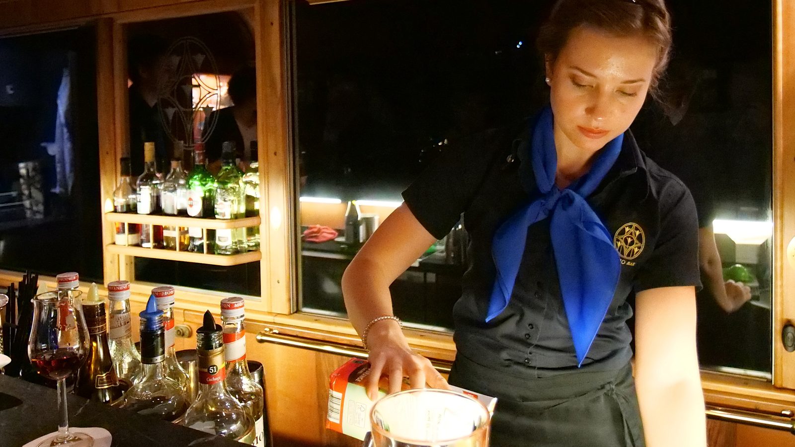 Eine Barkeeperin mixt an der Theke des Salonwagens PianoBar